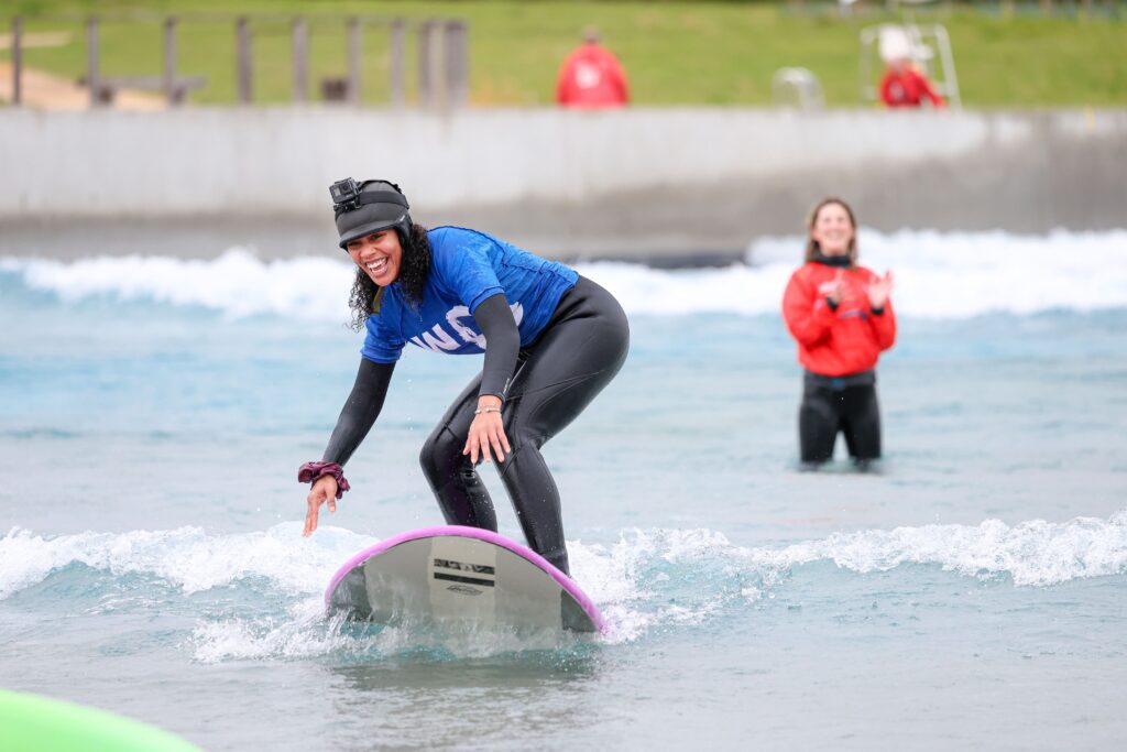 Female surfer pops-up on board.