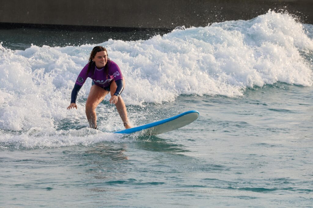 Women surfing on the waikiki wave at The Wave inland surf lake near Bristol