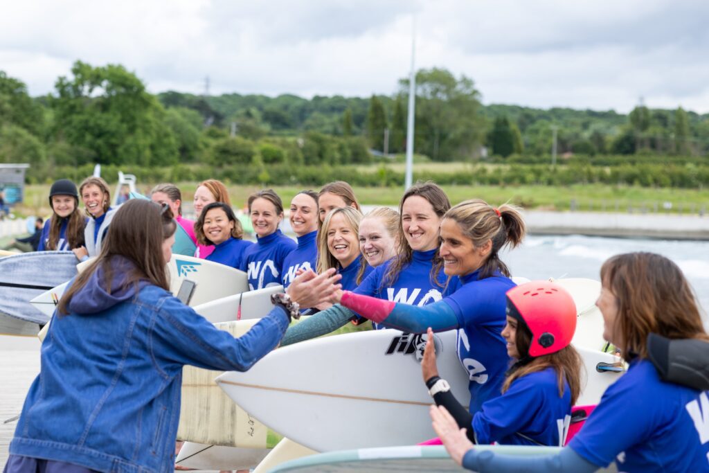 Jenny Jones and other women high five at The Wave's Sister Session women only surfing afternoons