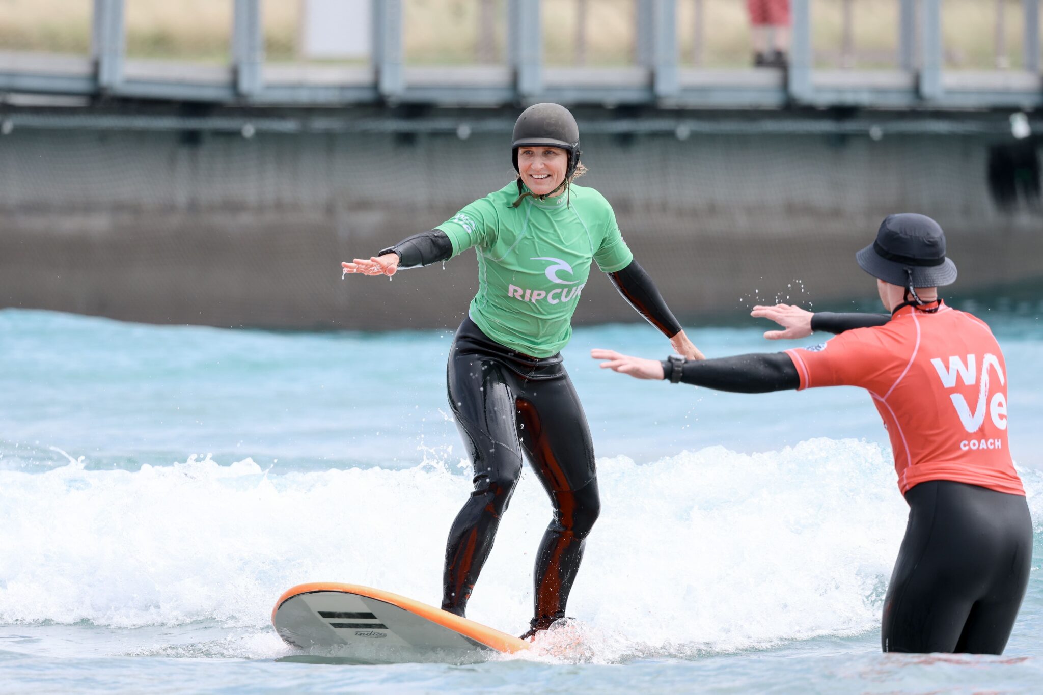 Woman learning to surf in an adult beginner lesson at The Wave