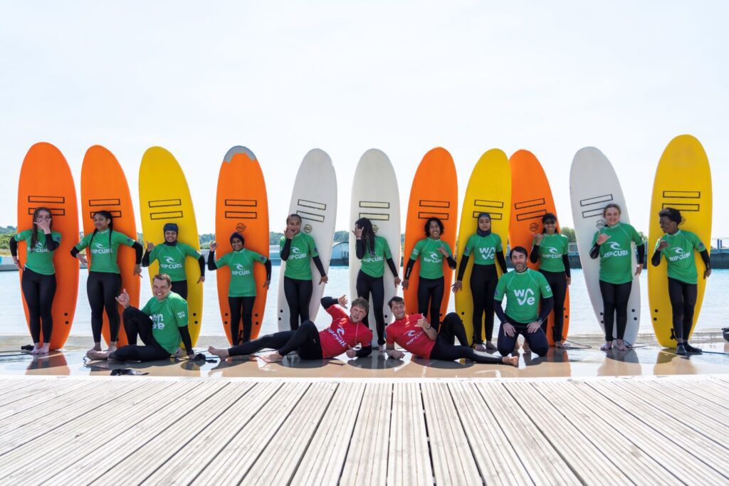 School children pose next to surfboards.